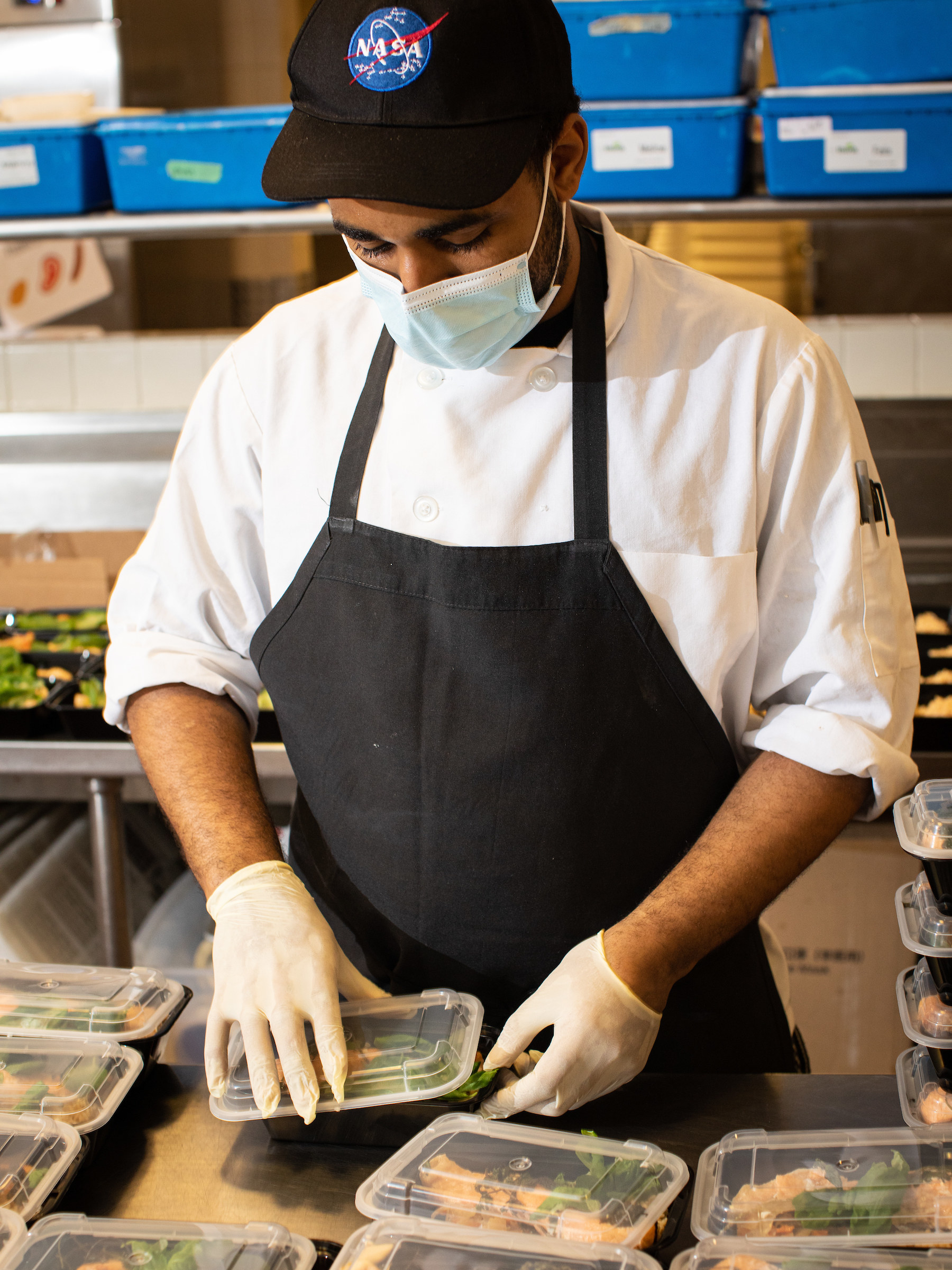 A chef prepares food in to-go containers.