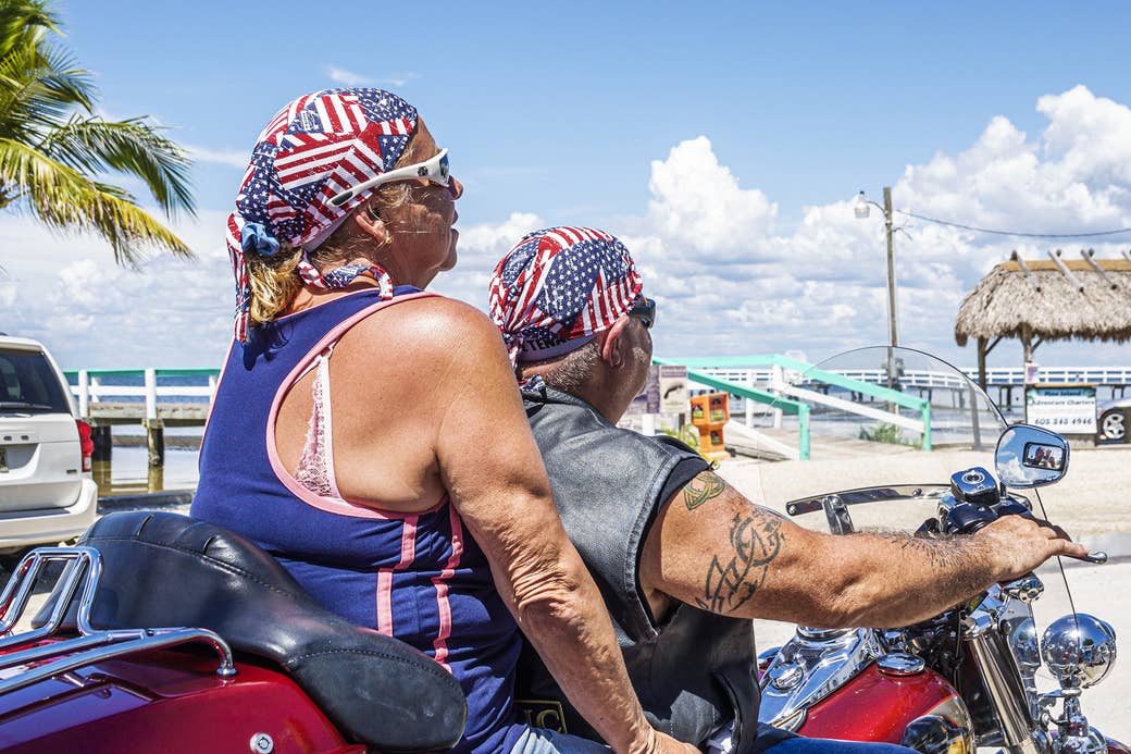 Two people on a motorbike wear the US flag on their heads