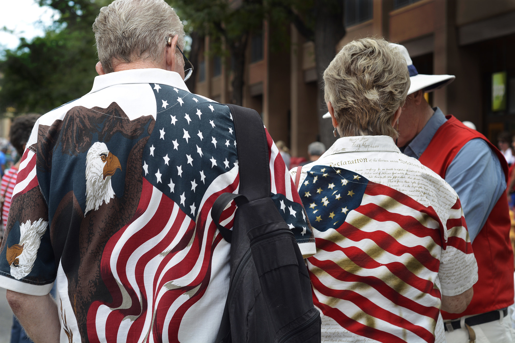 A man and a woman with their backs turned toward the camera wear flag-themed outfits, showing a bald eagle