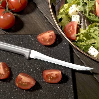 Serrated knife beside chopped cherry tomatoes