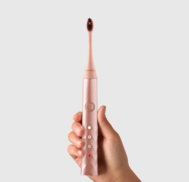 model holding up the rose gold burst electric toothbrush