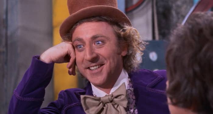 Gene WIlder as Willy Wonka wearing a tall top hat, fluffy bow tie, and velvet jacket