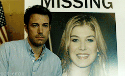 affleck&#x27;s character smiling next to a picture of his missing wife