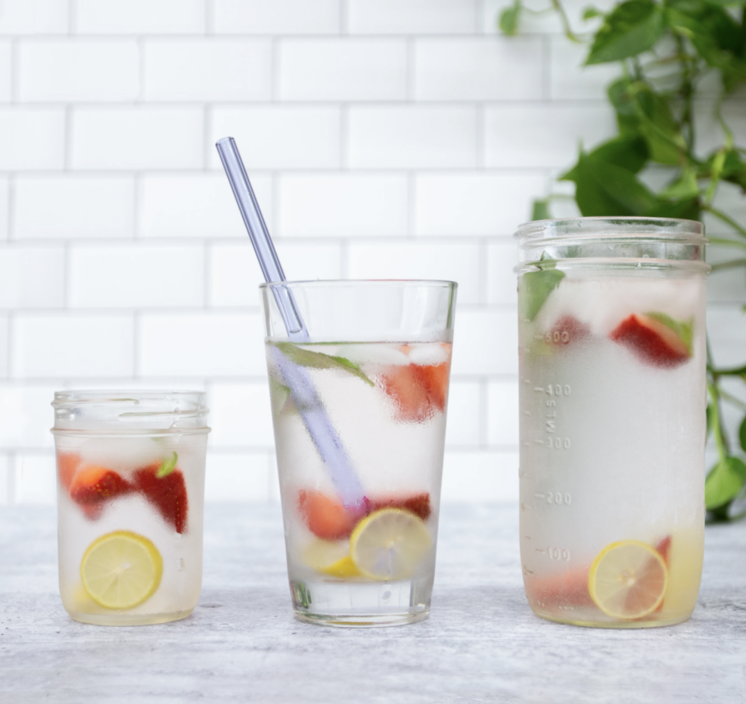 glass straws inside of a glass of water and fruit