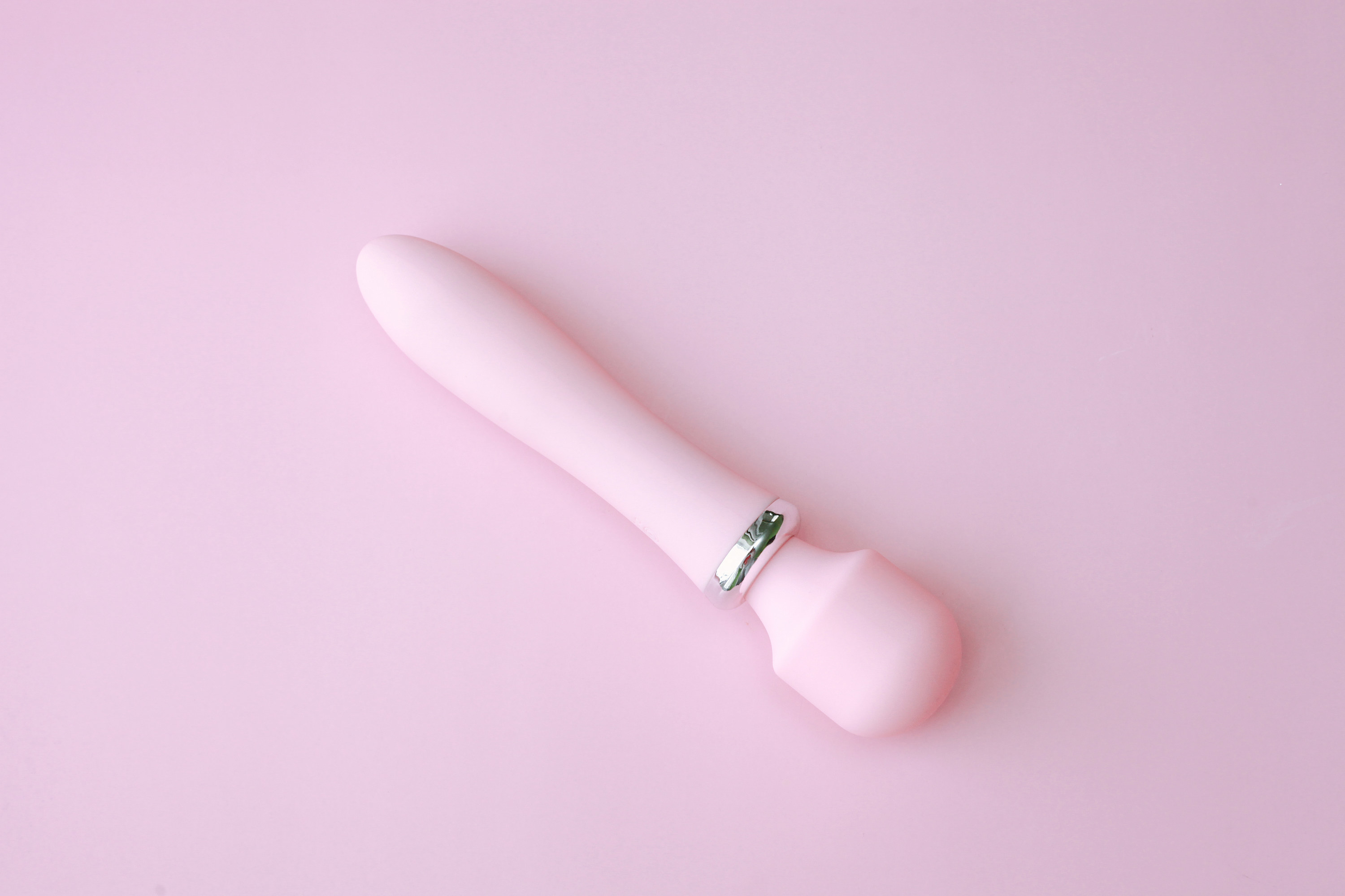 An image of a pink wand vibrator on a pink background