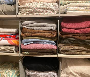 a reviewer photo of a closet full of linens and organized with the dividers 