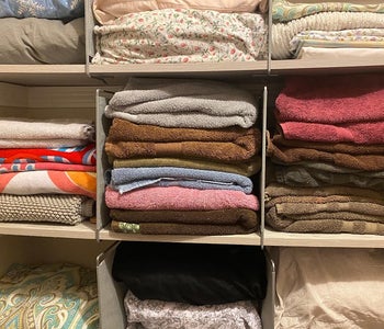 a reviewer photo of a closet full of linens and organized with the dividers 