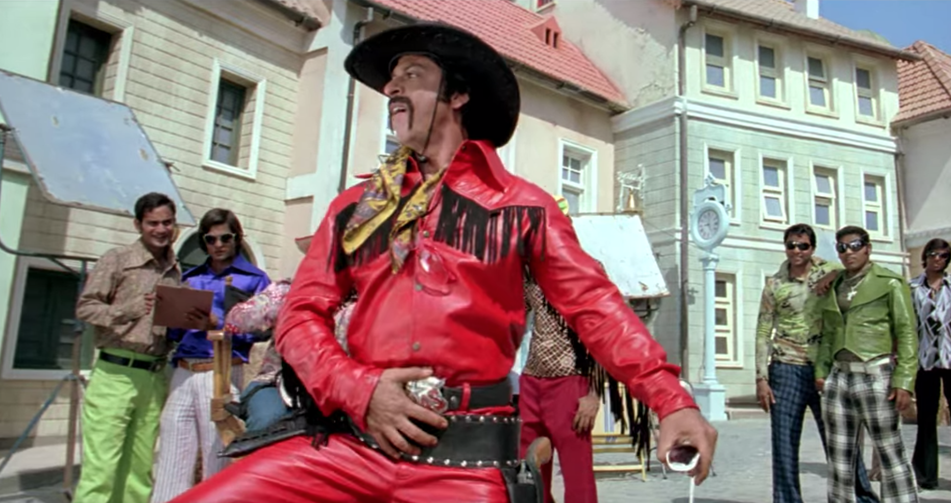 Om wears a red leather cowboy outfit with black tassels.