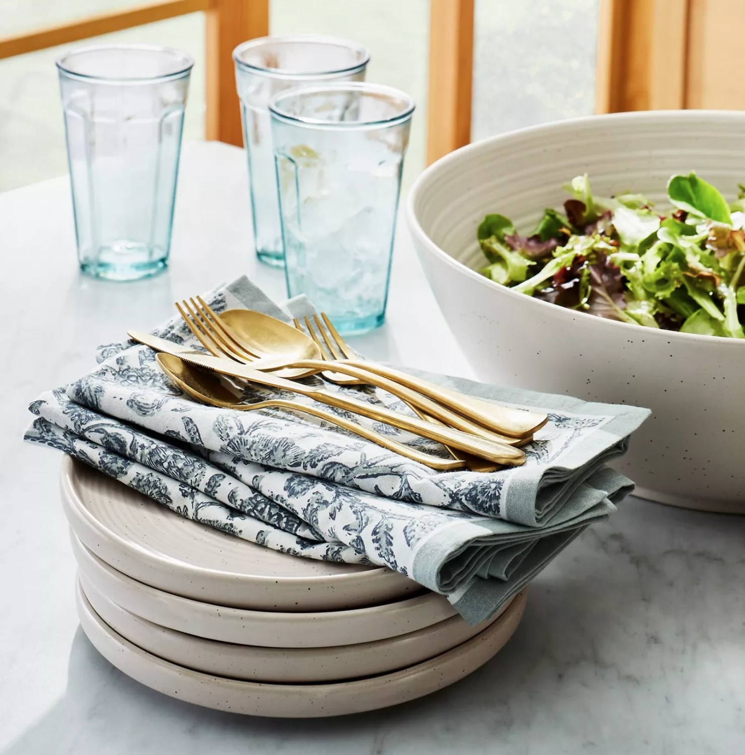the four pack of plates with a napkin and silverware on top and a salad bowl next to the plates
