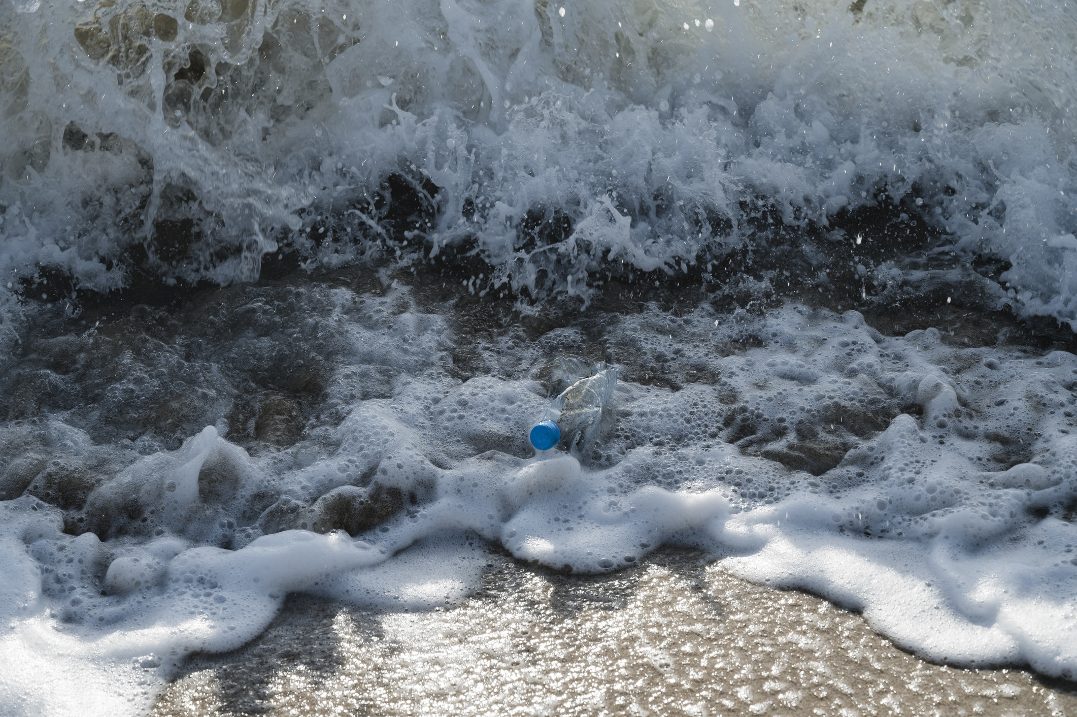 A plastic water bottle being swept into the ocean.