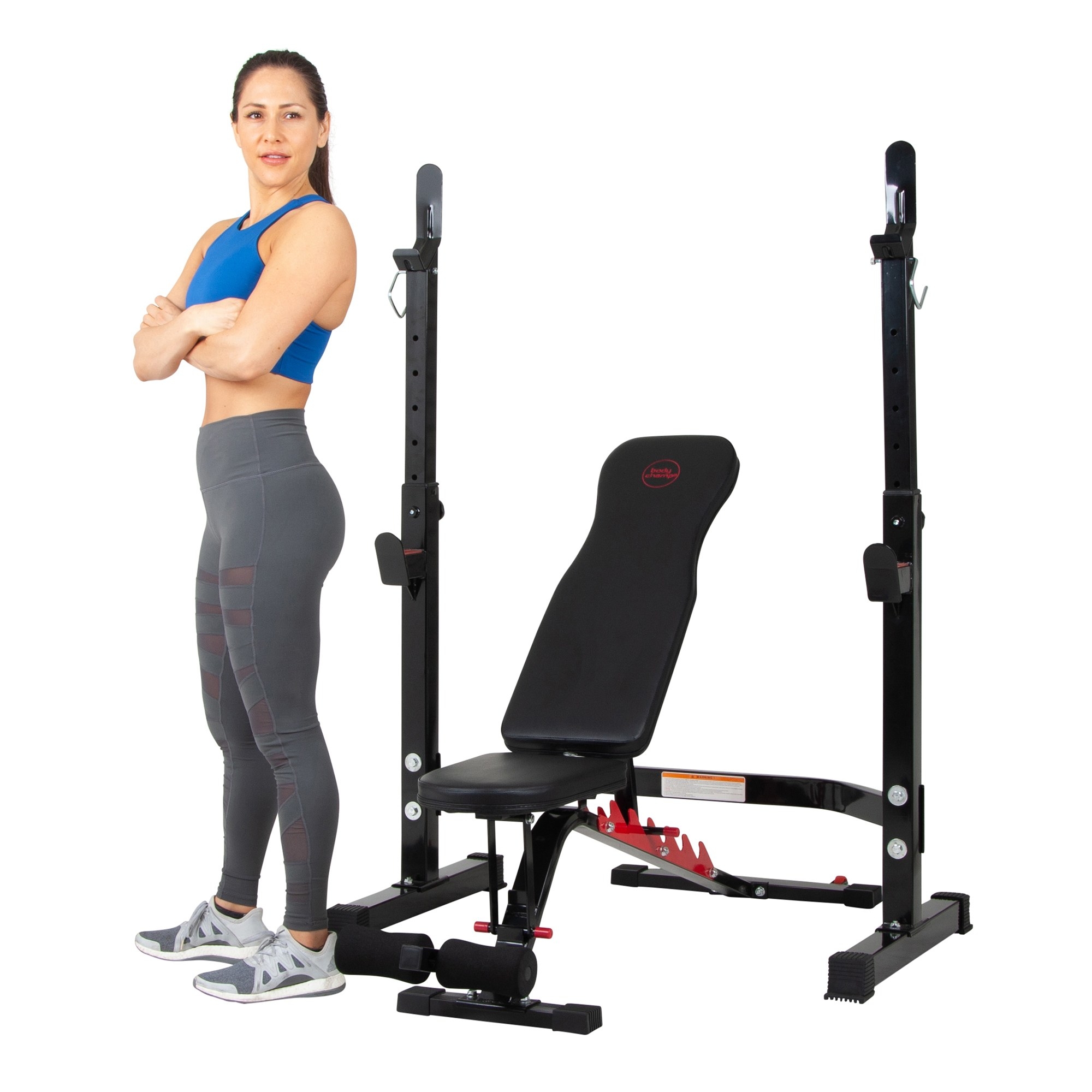 There is an adult standing next to the black and red bench and squat rack