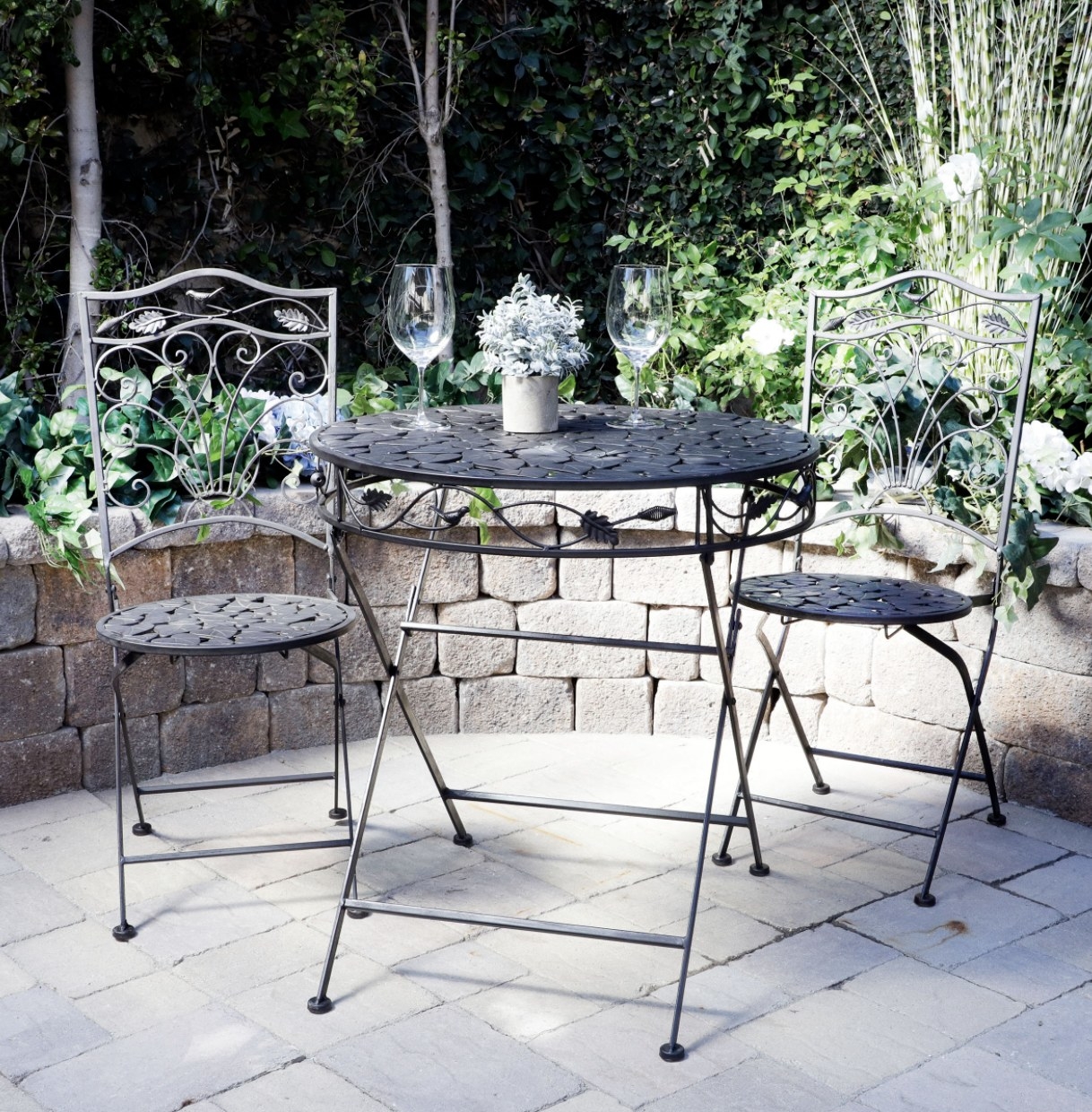 The black bistro set is outdoors and decorated with leafs and birds