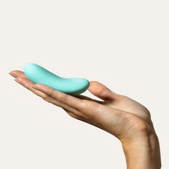 A hand holds a light blue palm vibrator
