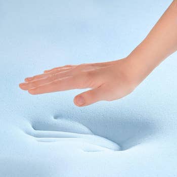 Model placing hand on cooling mattress topper