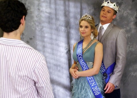 Hannah wears a homecoming queen sash and crown and is hugged from behind by her boyfriend on Pretty Little Liars