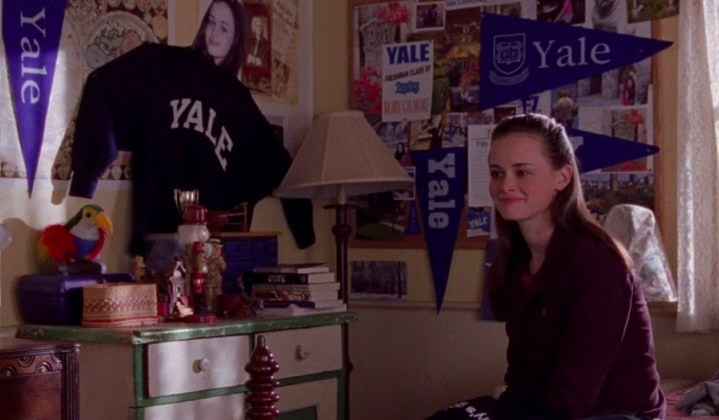 Rory sits in her bedroom that is decorated with Yale paraphernalia  in Gilmore Girls