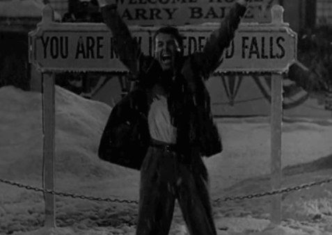 George Bailey cheers in front of the Bedford Falls sign in the snow in It&#x27;s A Wonderful life