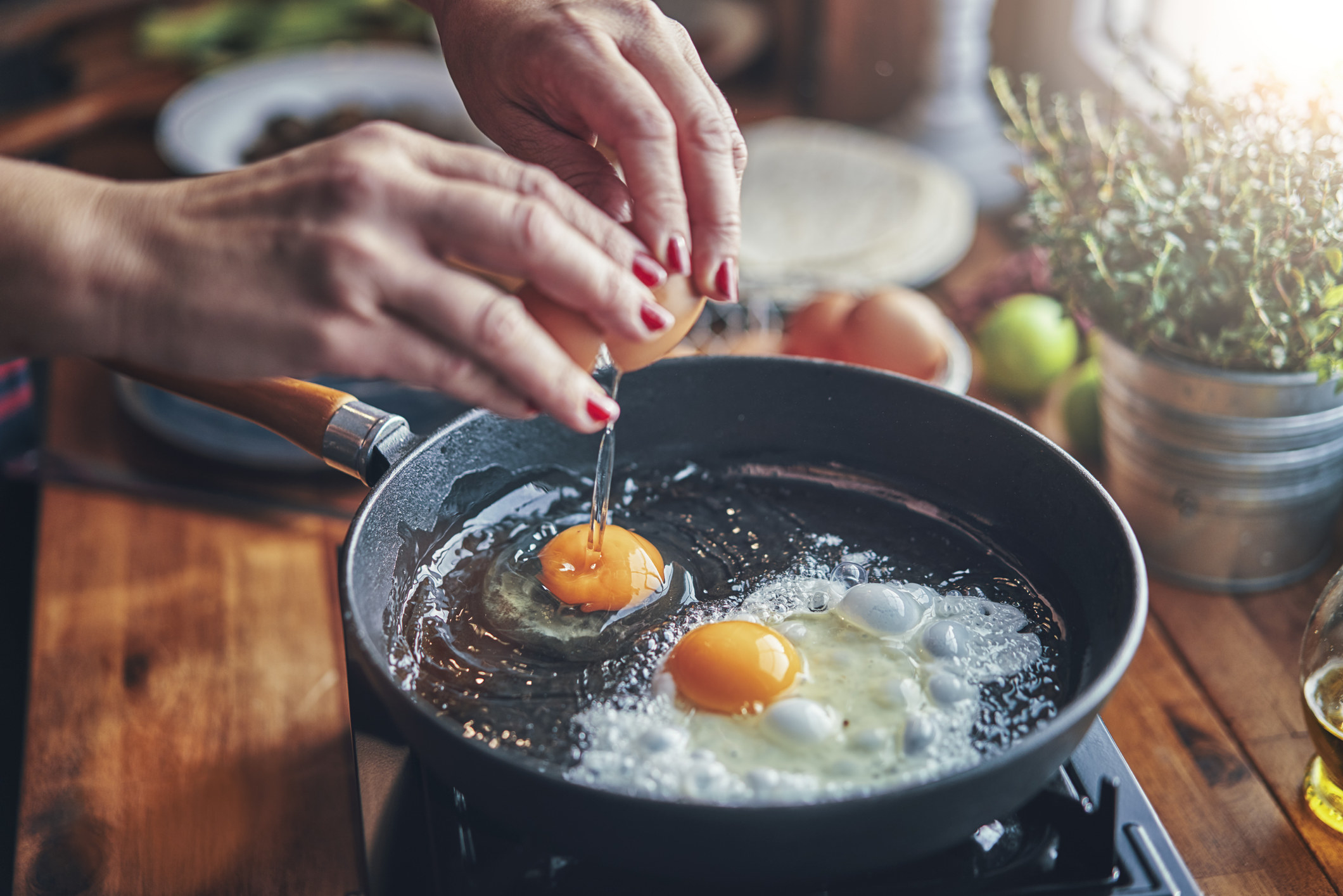 Someone frying two eggs in a cast iron skillet.