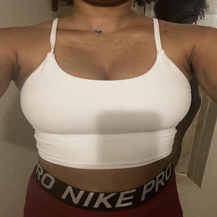 a reviewer selfie of someone wearing the sleeveless cropped top in white 