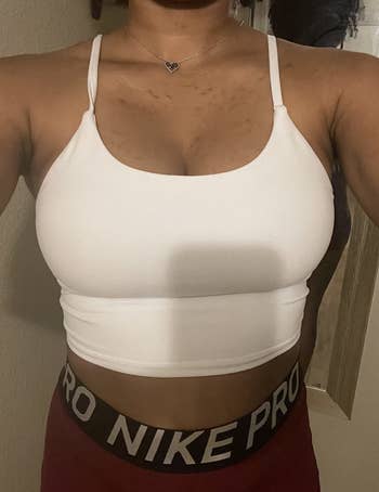 a reviewer wearing the sleeveless cropped top in white 