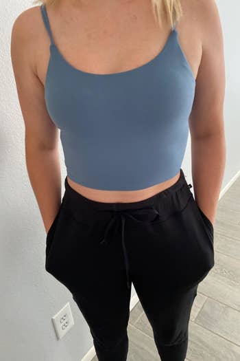 a reviewer wearing the sleeveless cropped top in light blue with black pants 