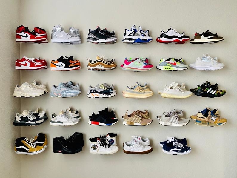 a display of 29 clear plastic wall mounts with sneakers displayed on them 