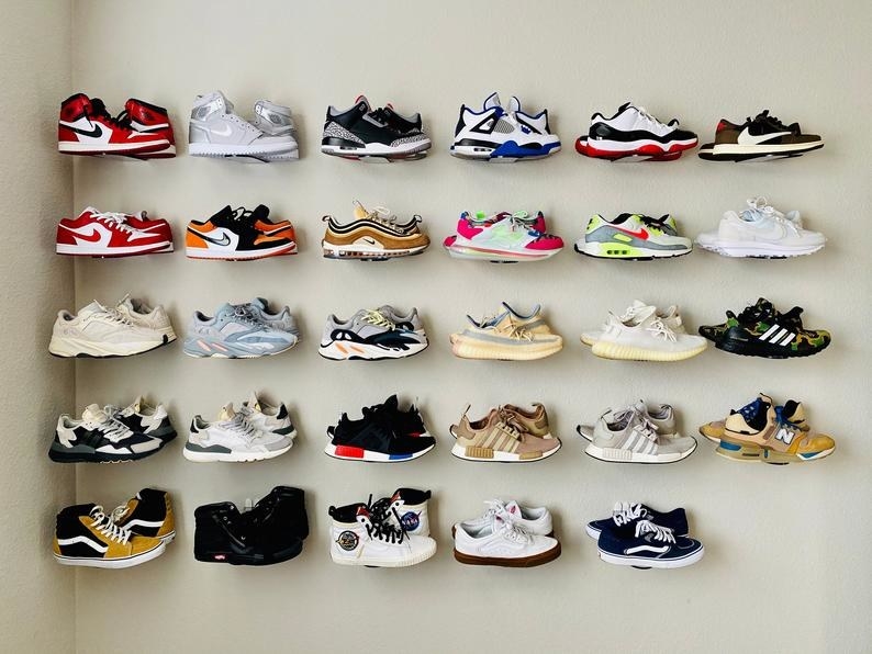a display of 29 clear plastic wall mounts with sneakers displayed on them