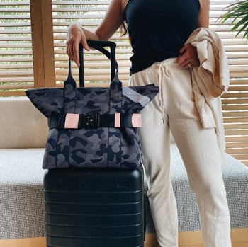 model standing next to a suitcase with a bag on top that's attached with a travel belt