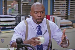 Terry from "Brooklyn Nine-Nine" holding a cup of yogurt and opening his eyes wide