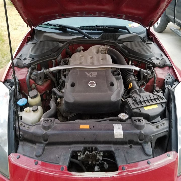 reviewer's photo of the dirty car parts under their hood