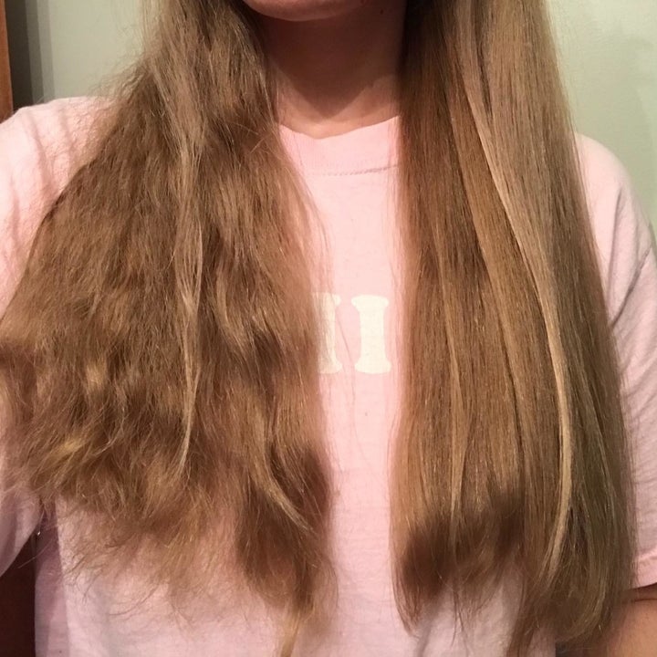 reviewer with thick, wavy hair showing one side of their side wavy and a little frizzy and the other side straight and smooth