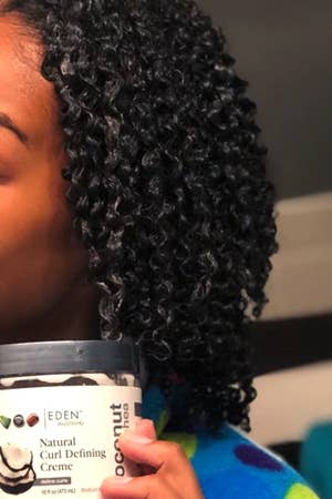 model with kinky hair holding the jar of product 