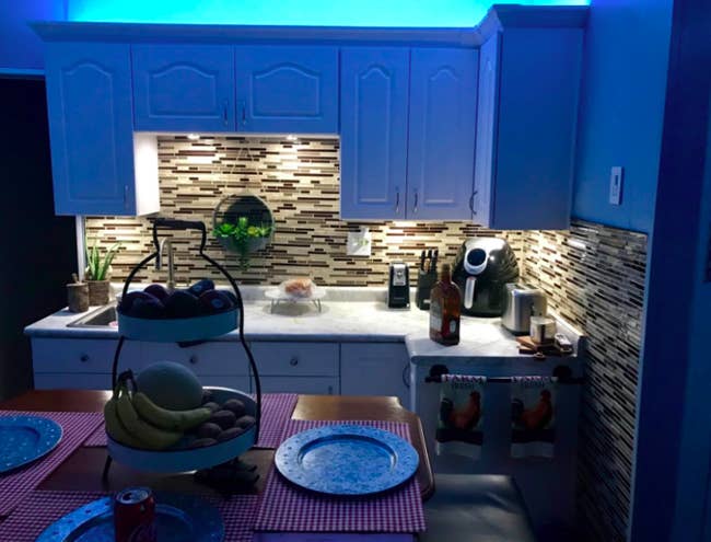 A reviewer's kitchen with the space above the cabinets lit up blue and the space below the cabinets being a more neutral color