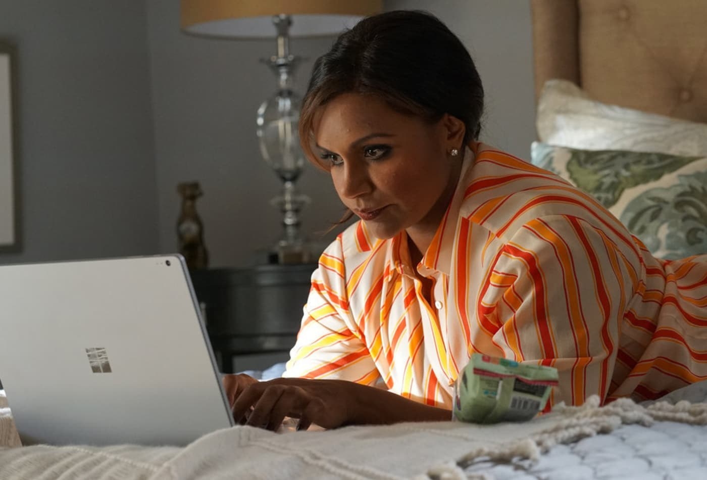 mindy kaling types on a laptop