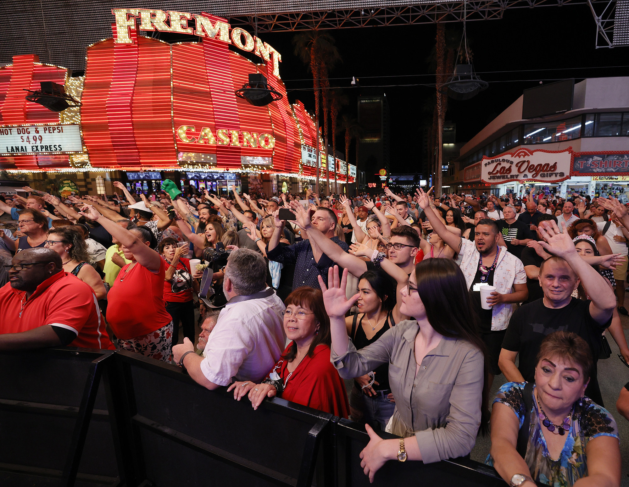 A crowd of people raise their hands as they watch a concert on a packed street in Las Vegas