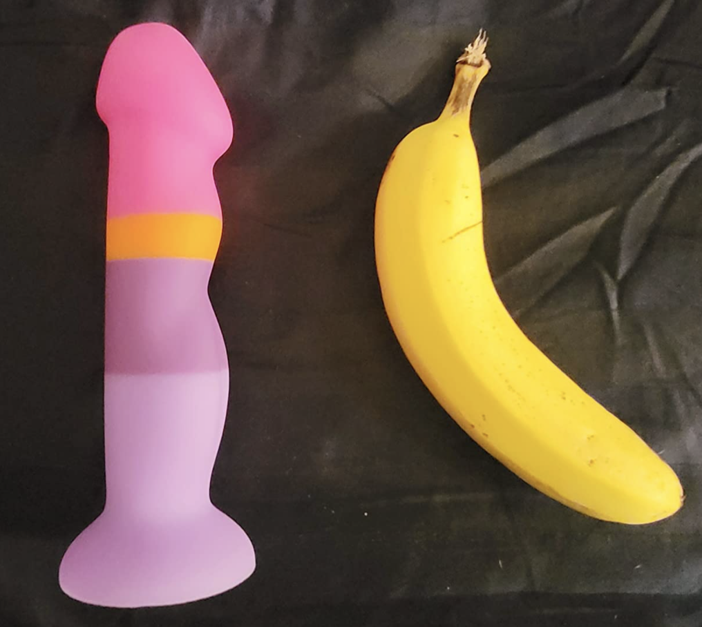 Pink striped silicone dildo next to a banana to show it&#x27;s about the same size