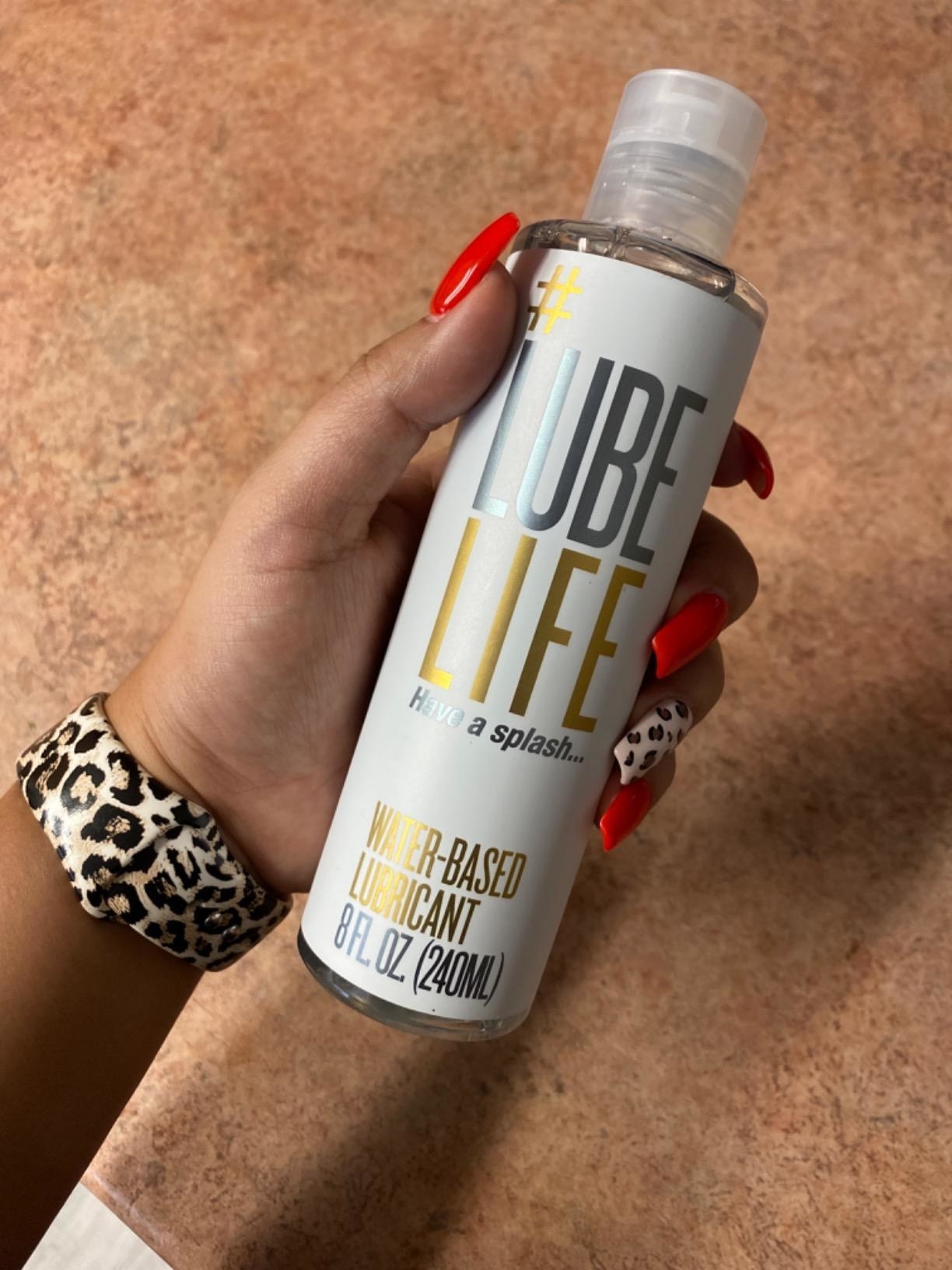 Manicured hand holding bottle of Lube Life lubricant