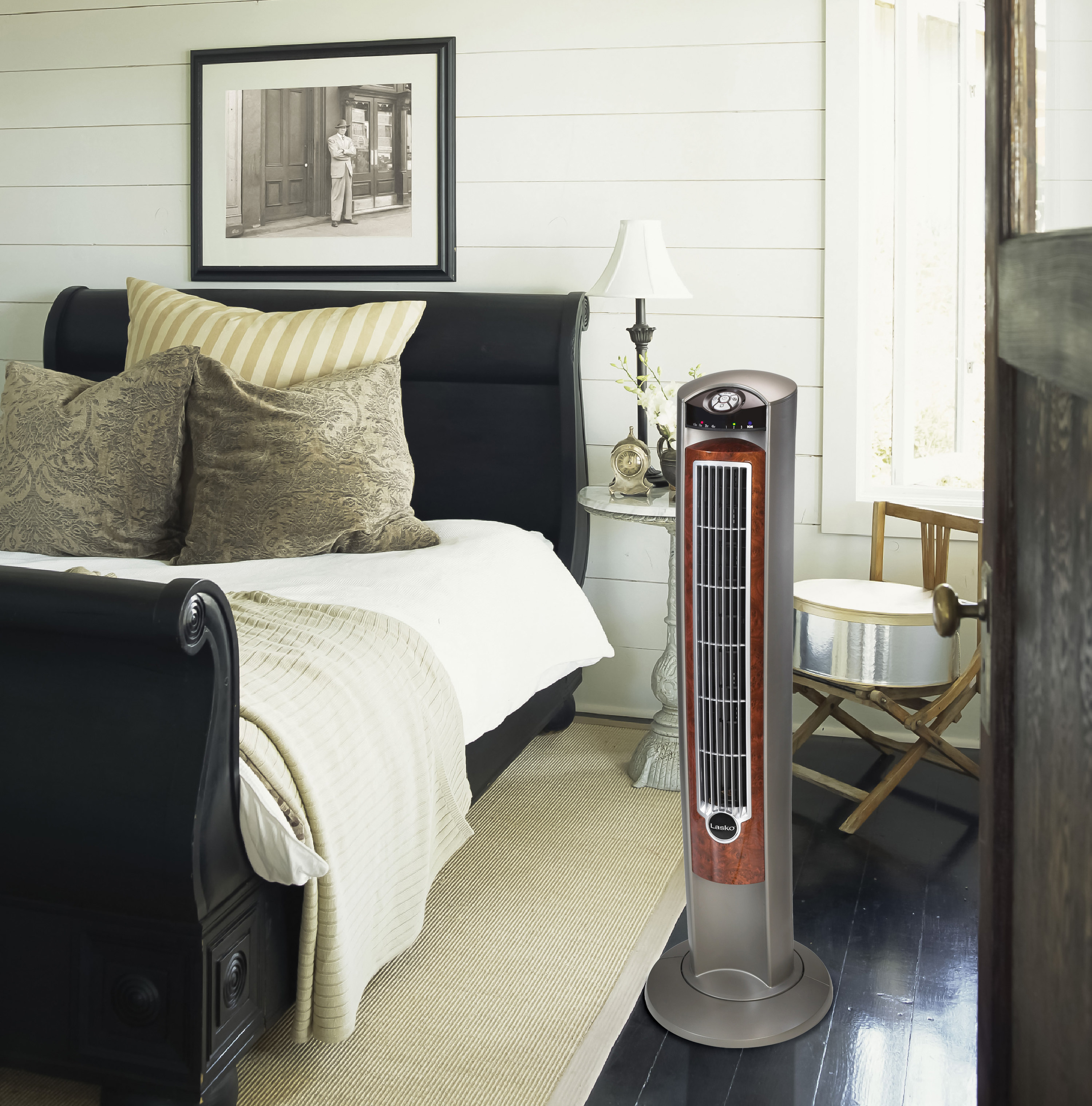 The fan in a bedroom. It&#x27;s gray with wood detailing and a silver grille.