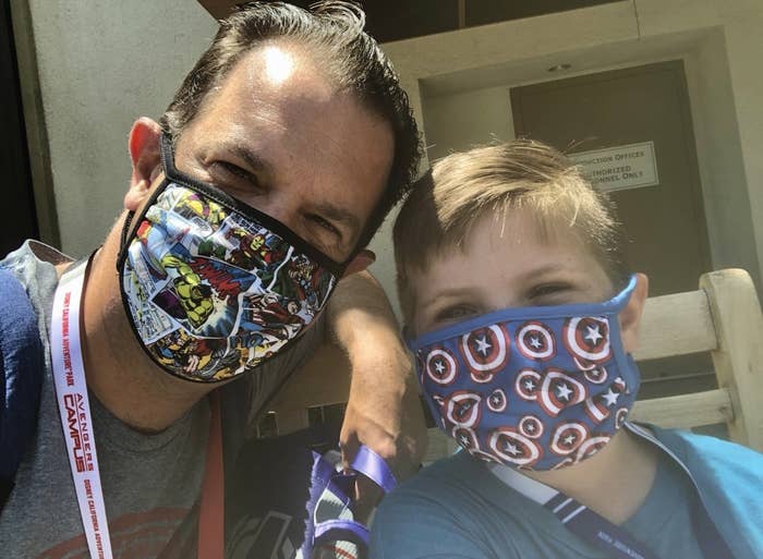 A father and son lean close wearing matching Marvel face masks