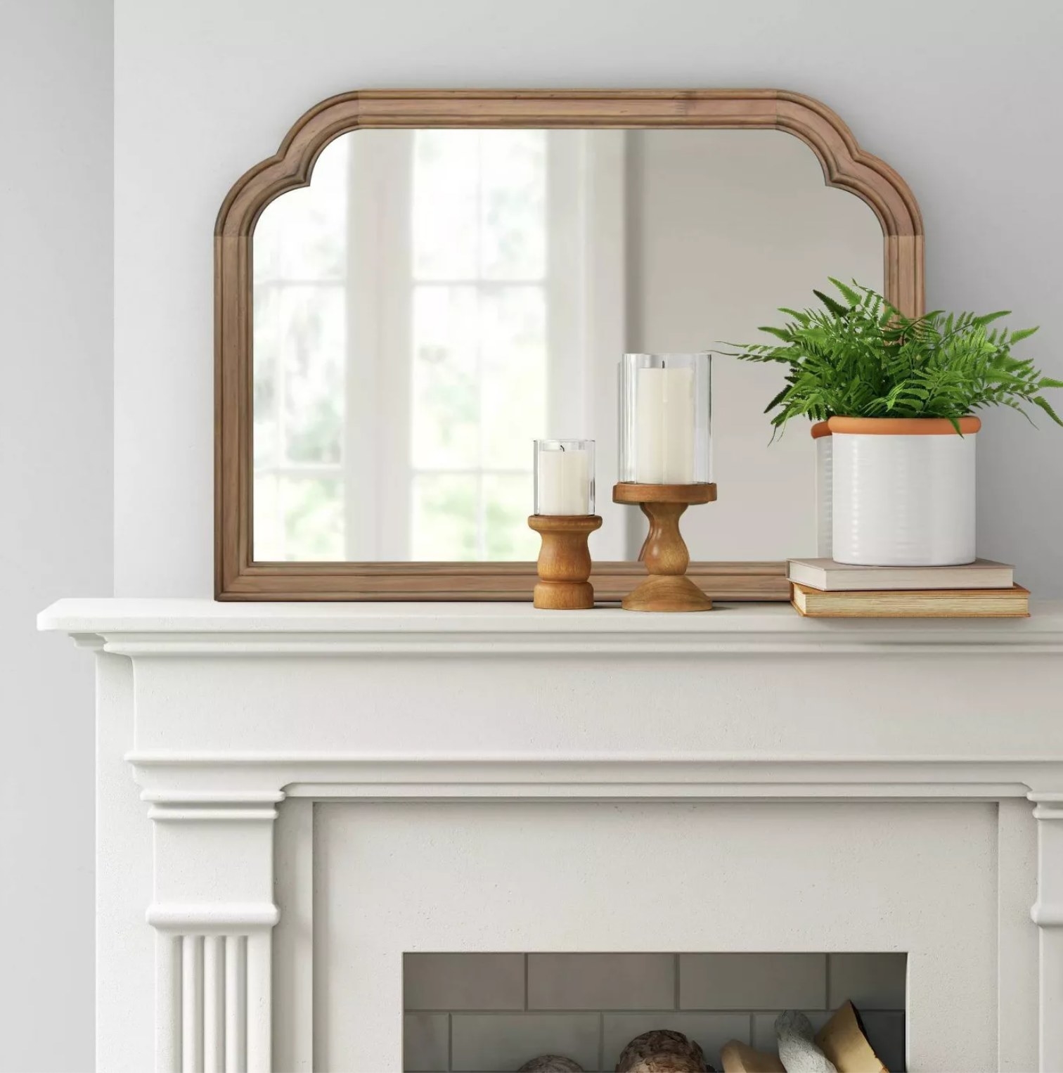 the mirror on a mantle with candles and a plant placed in front of it