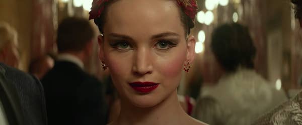 Dominika Egorova smiling in a small, stilted way in "Red Sparrow"