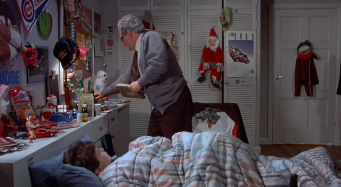 The boy lies in bed and the grandfather stands next to it holding a book in The Princess Bride