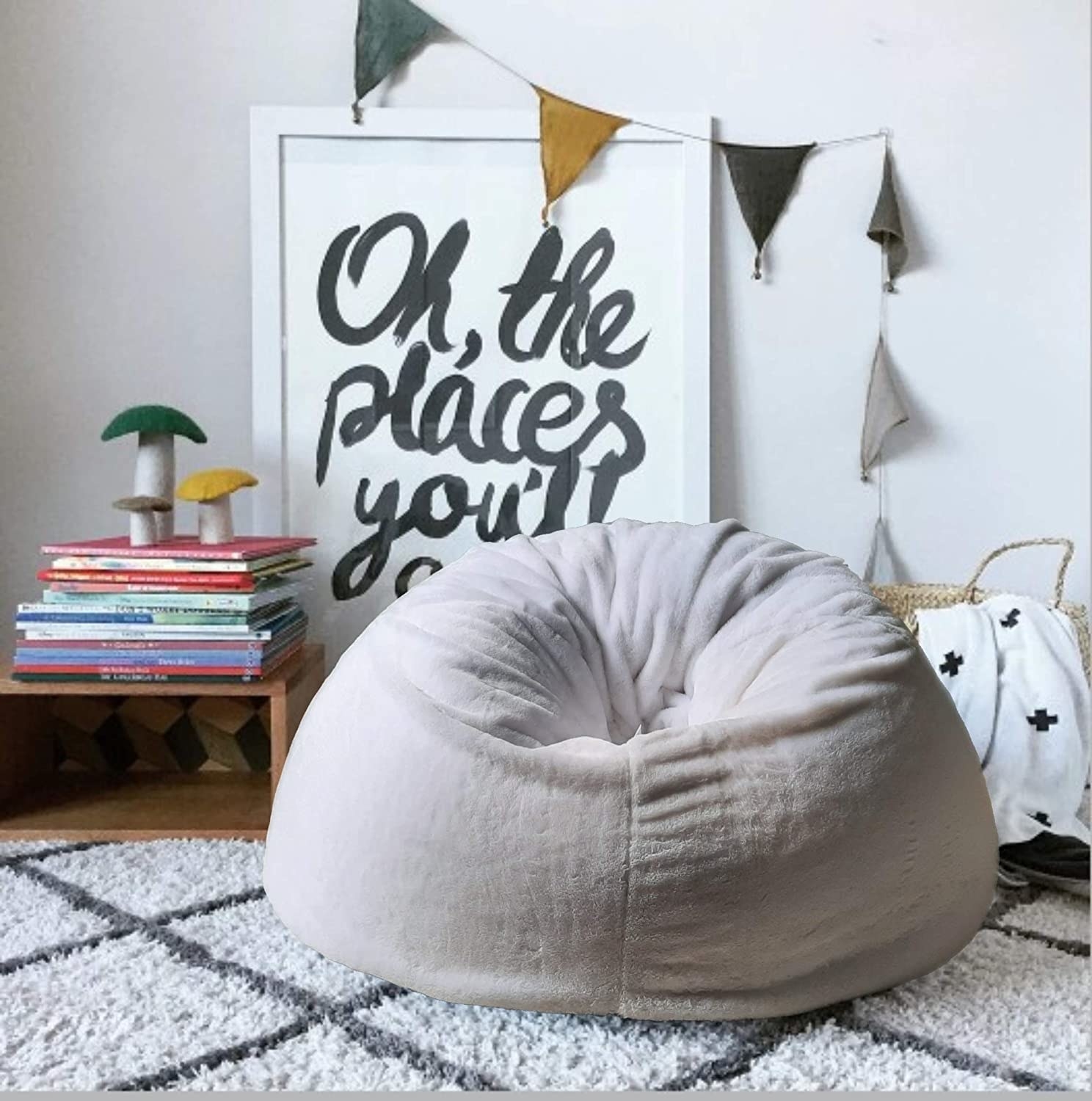 A fluffy bean bag chair on the rug next to a poster and some books and a basket 
