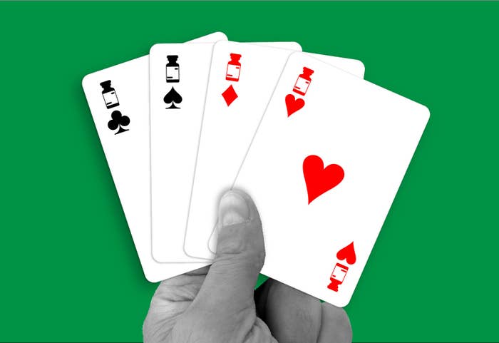 A hand holds four cards of different suits, each with images of a medication container