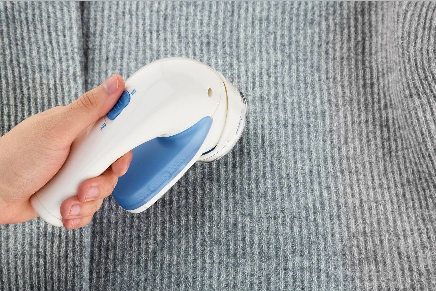 A blue and white fabric shaver in use