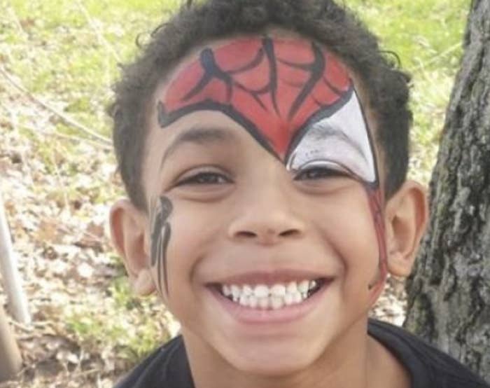 A smiling little boy wears Spider-Man face paint