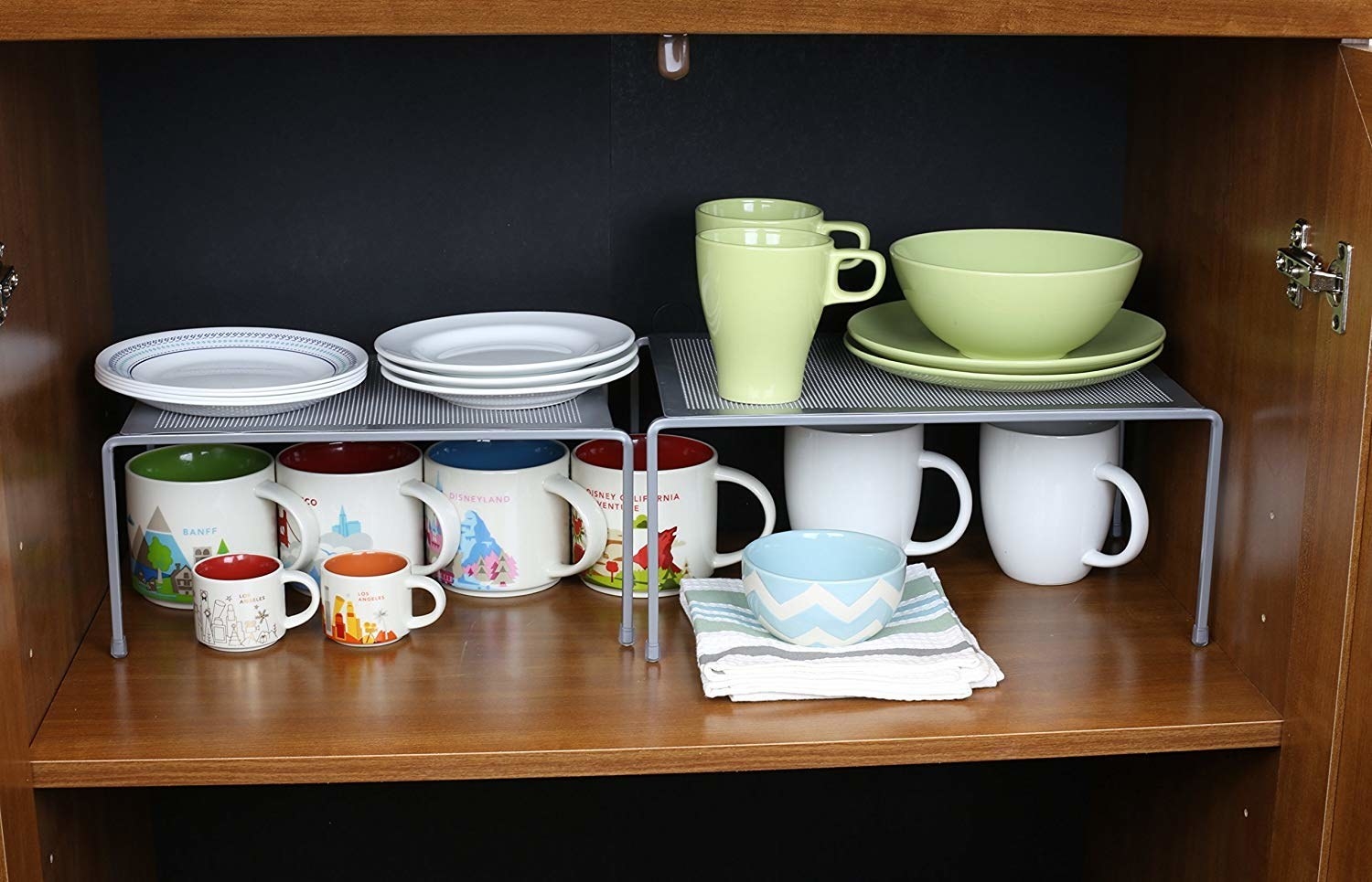 A silver expandable rack with mugs at the bottom and plates and cups at the top