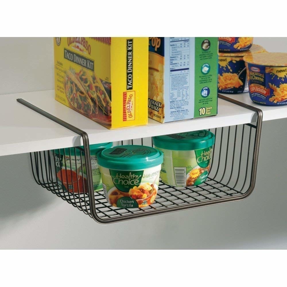 An under-the-shelf basket with cans of soup on it 