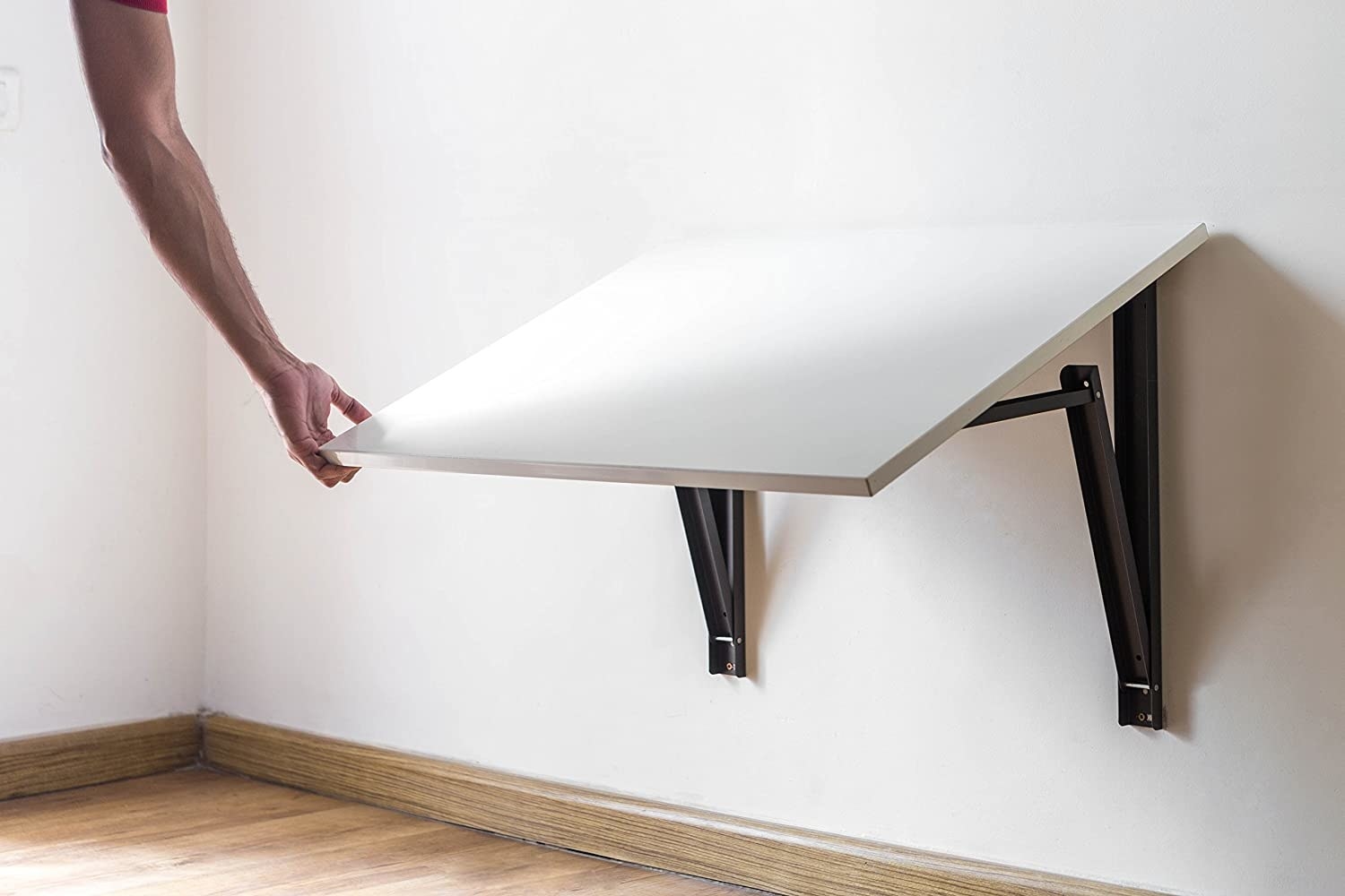 A white foldable table being put back into place by an arm 