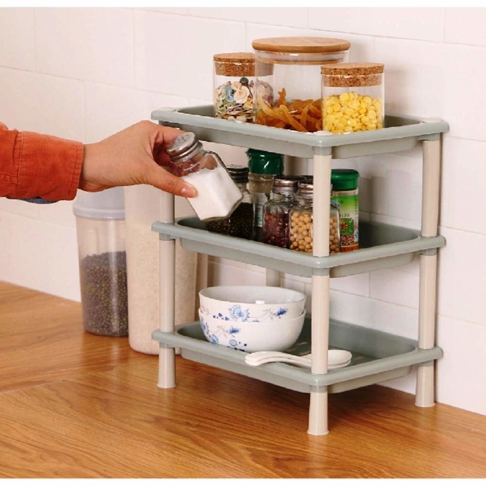 A three-tier rack with bowls, spice containers and snacks on it 